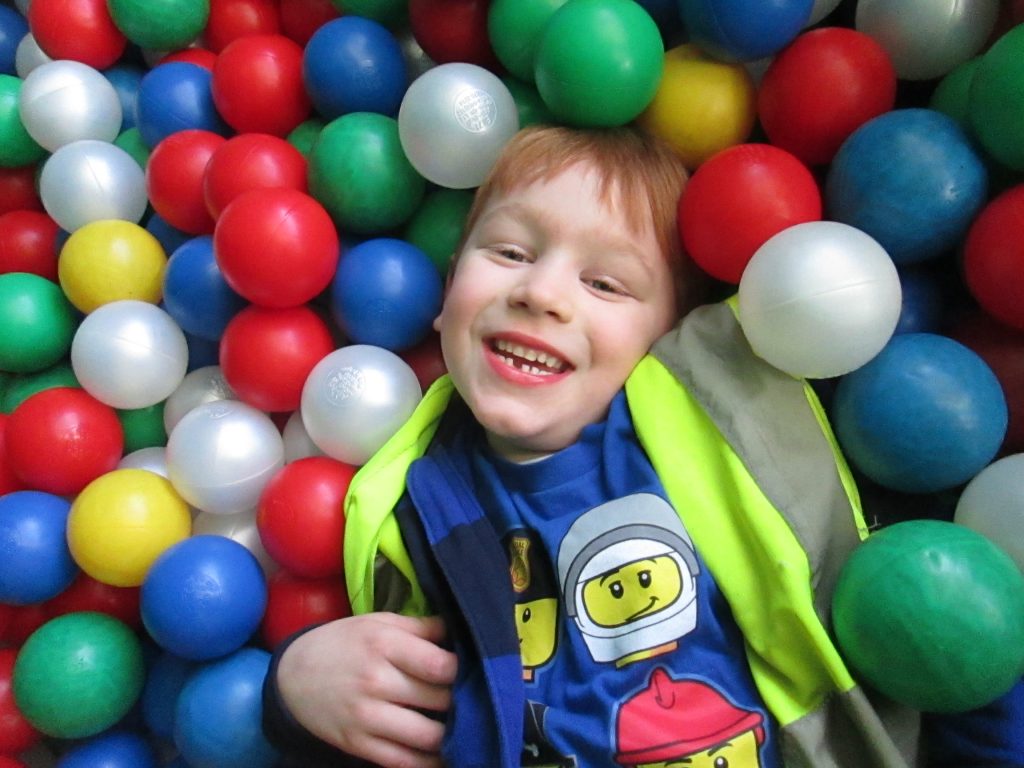 the Gower School Boy Smiling in a Ball Pit During Holiday Fun Club