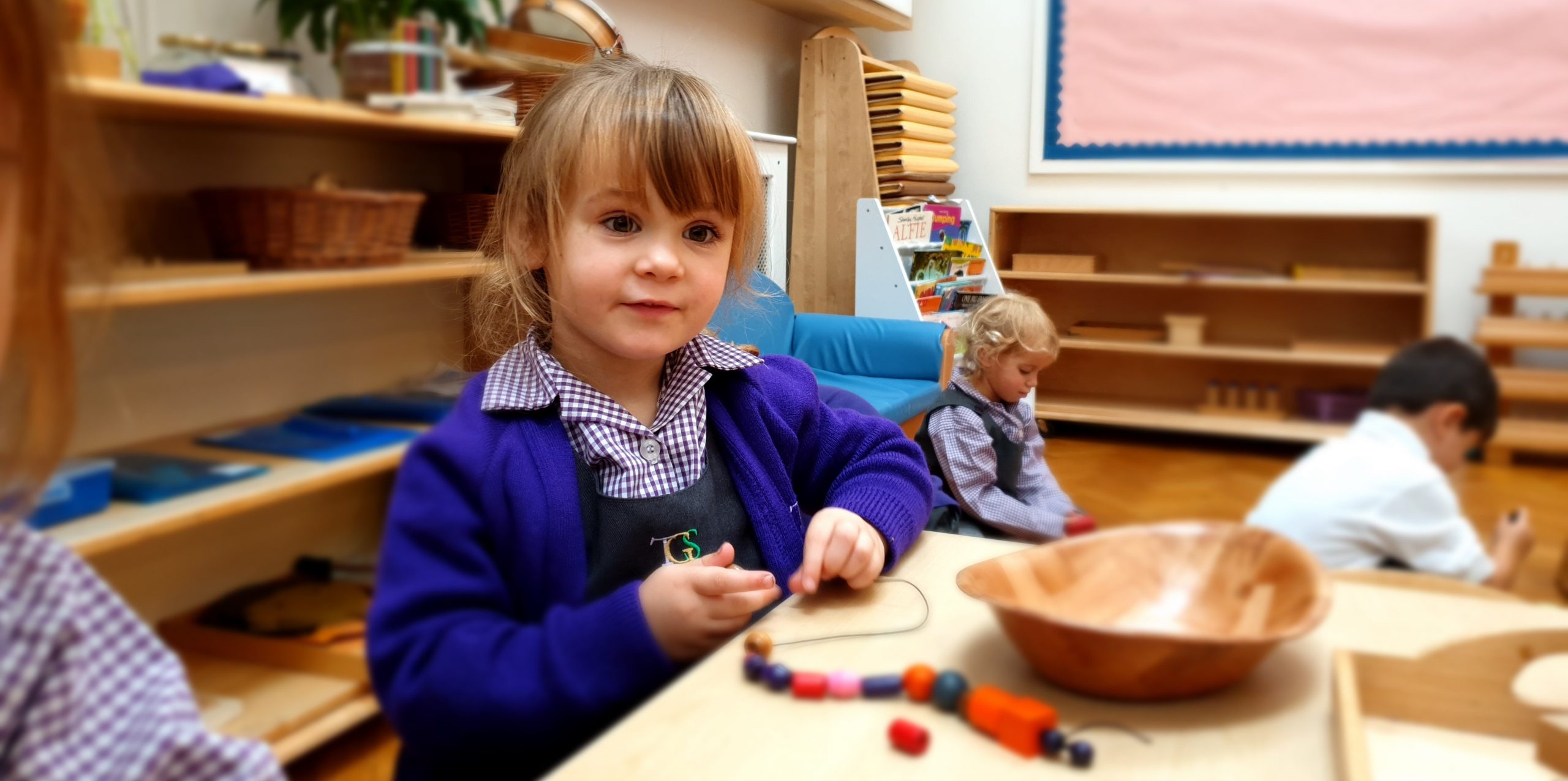 a Young Girl Engages with Threading Activities at the Gower School's Montessori Nursery classroom in London.