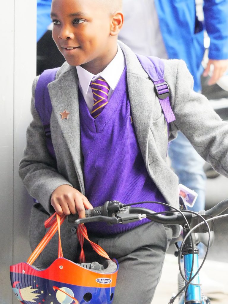 A young Gower School pupil riding his bike into the school in the morning.