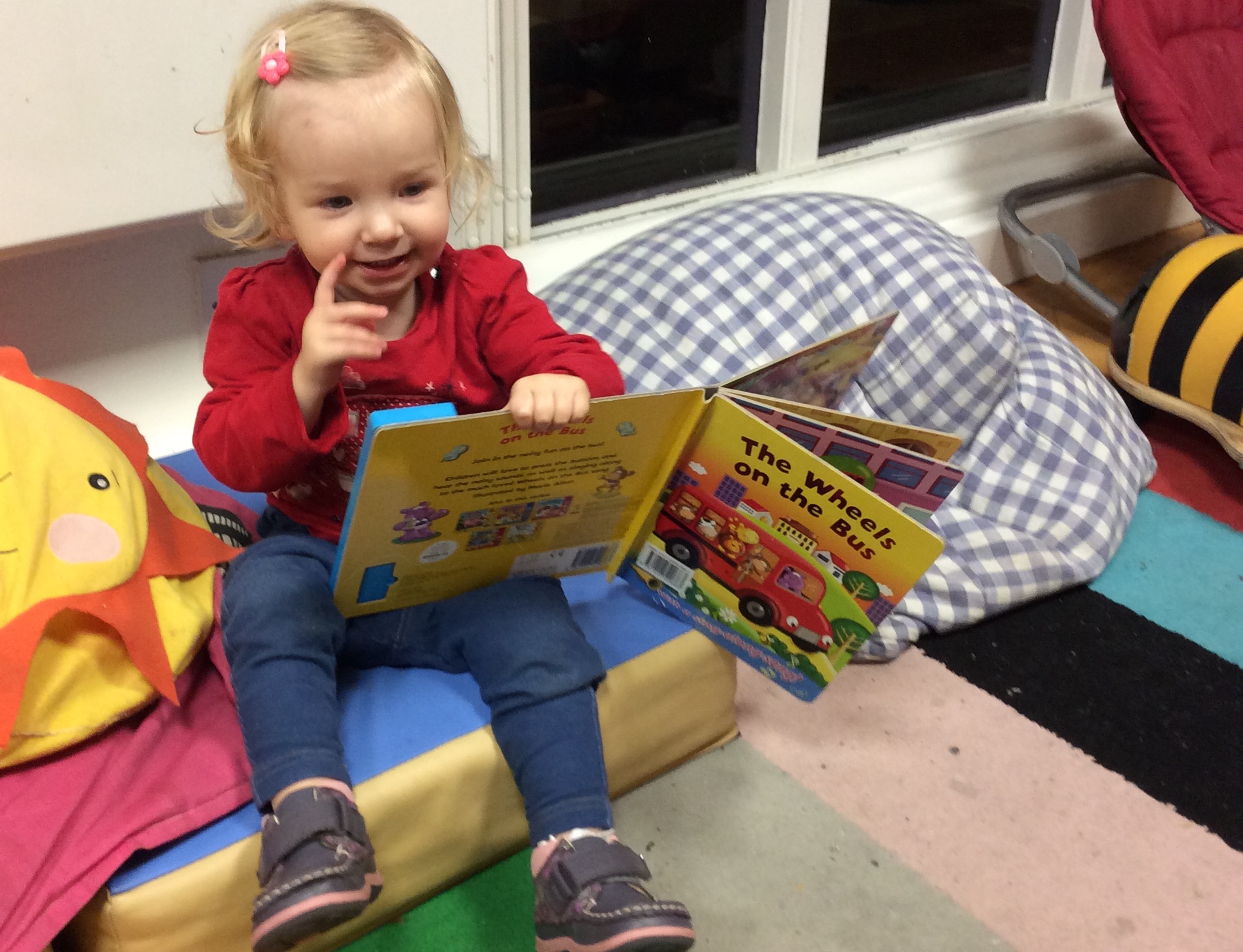 a Happy Toddler Reads a Book in the Gower School, Montessori Nursery.