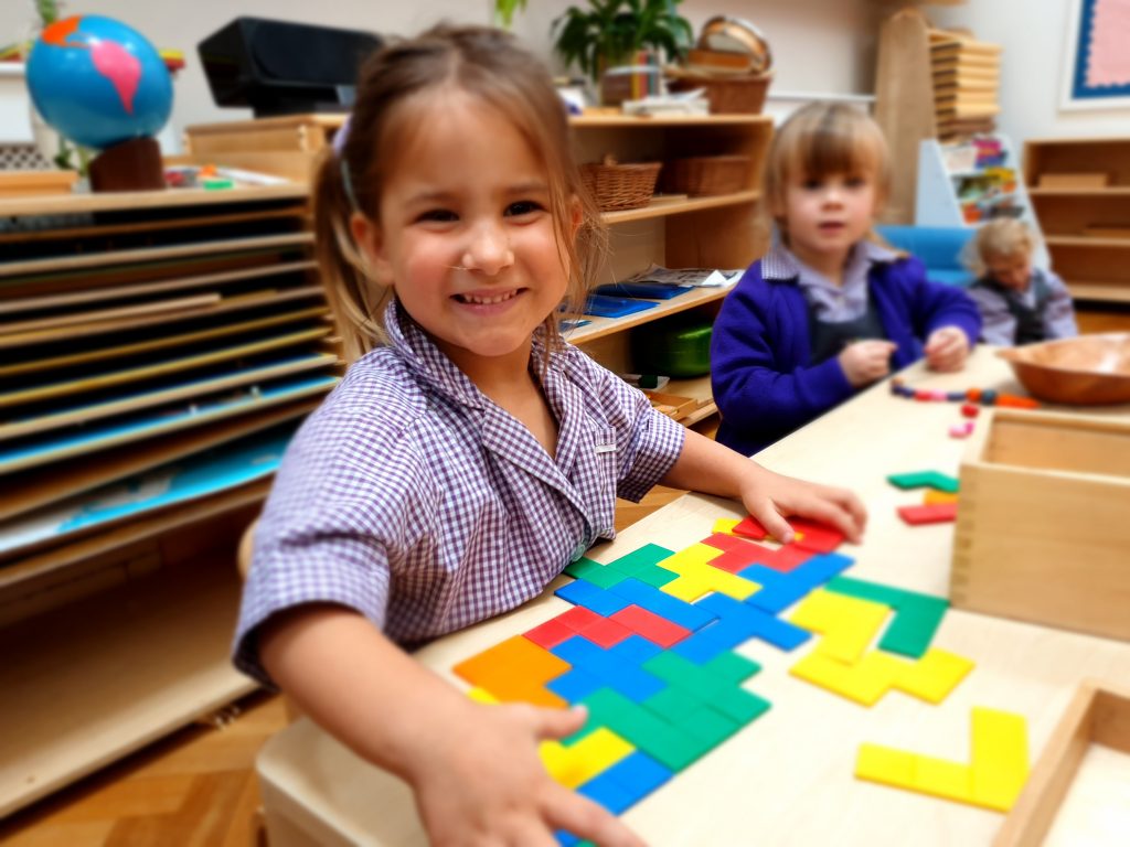 a Smiling Girl Enjoying Her Work Cycle Activity in the Gower School Montessori Nursery.