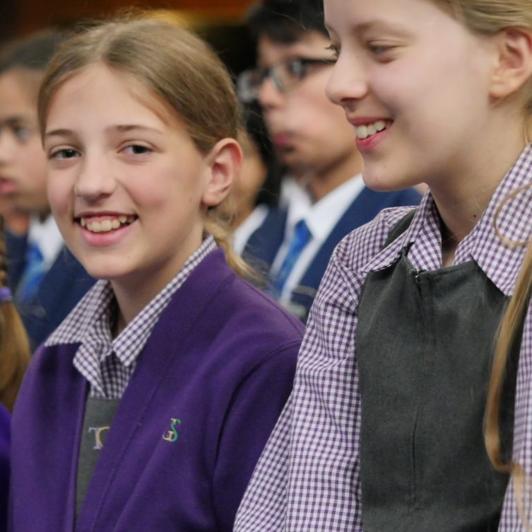 a Girl in Uniform Smiling at the Camera Amidst a Group of Her Classmates.