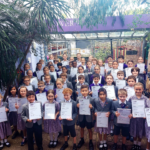 Over 50 Gower School children powing with their LAMDA certificates in the school courtyard.