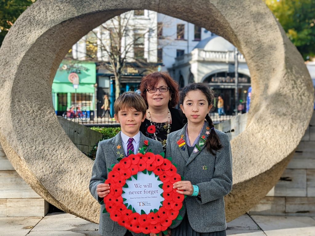 the Gower School Head Boy and Heag Girl Pose with a Remembrance Sunday Wreath and Principal Emma Gowers.