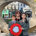 The Gower School Head Boy and Heag Girl pose with a remembrance sunday wreath and Principal Emma Gowers.