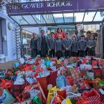 The Gower School Council stands before the sea of donated Christmas gifts.